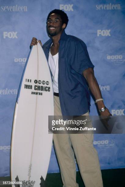 American basketball player Kobe Bryant poses with a surfboard in the press room of the inaugural Teen Choice Awards, held at the Barker Hangar, at...