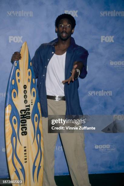 American basketball player Kobe Bryant poses with a surfboard in the press room of the inaugural Teen Choice Awards, held at the Barker Hangar, at...