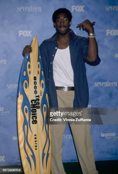 American basketball player Kobe Bryant poses with a surfboard in the press room of the inaugural Teen Choice Awards, held at the Barker Hangar, at...