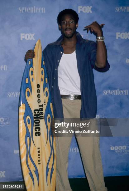 American basketball player Kobe Bryant poses with a surfboard in the press room of the inaugural Teen Choice Awards, held at the Barker Hangar, at...