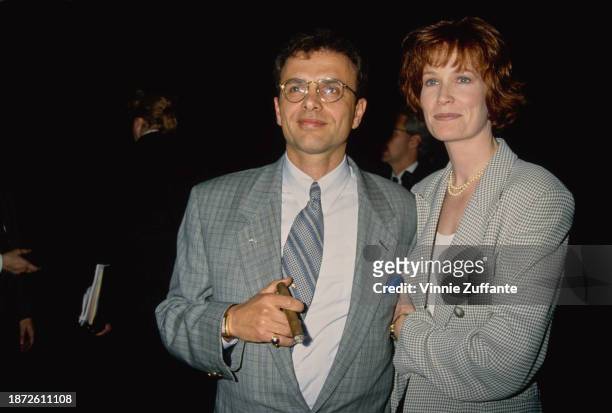 American actor Joe Pantoliano, wearing a checked grey suit jacket over a white shirt with a diagonally-striped tie, holding a lit cigar, and his...