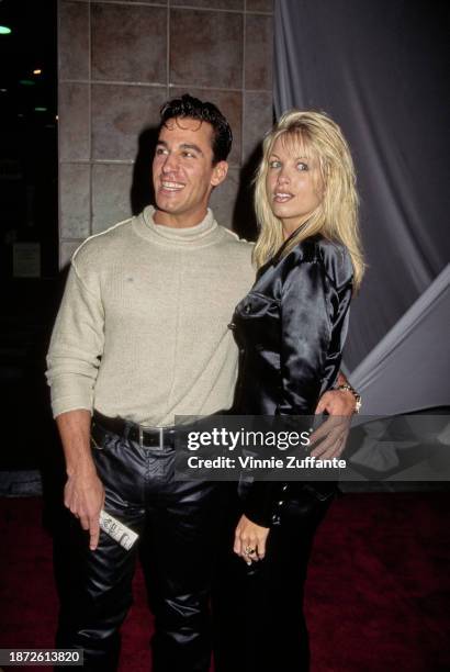 American actor Dan Cortese, wearing a beige crew neck sweater with black leather trousers, his arm around the waist of his wife, Dee Dee Cortese at...