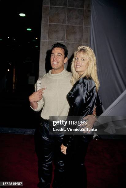 American actor Dan Cortese, wearing a beige crew neck sweater with black leather trousers, his arm around the waist of his wife, Dee Dee Cortese at...