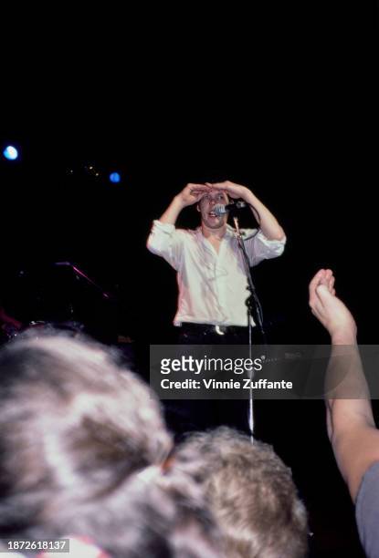 American singer, songwriter and musician Steve Forbert shields his eyes as he looks out over the audience attending his concert, United States, circa...
