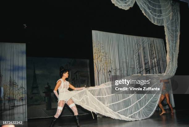 Fashion model walks the runway, wearing a white dress with a long white train and white evening gloves designed by French fashion designer Jean Paul...