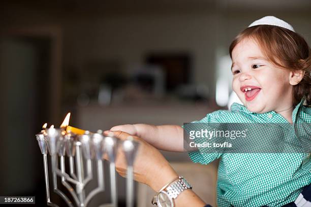 little boy lighting a silver menorah - chanoeka stockfoto's en -beelden