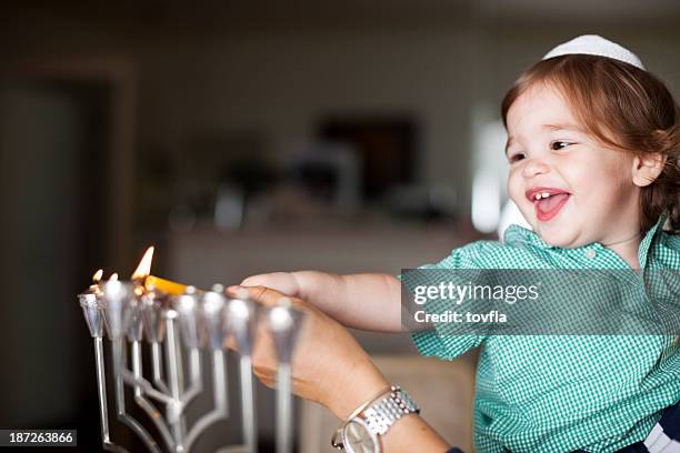 little boy lighting a silver menorah - hanukkah stock pictures, royalty-free photos & images