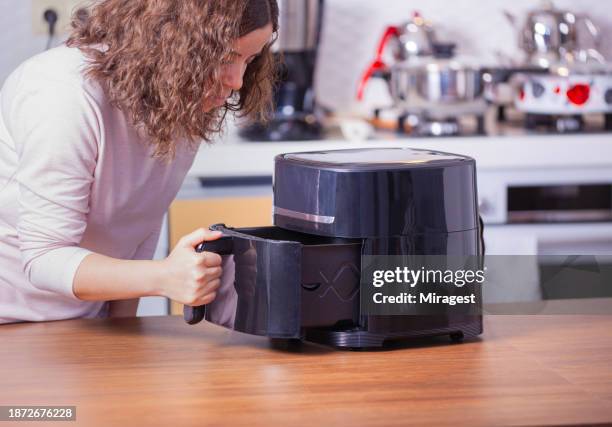 woman cooking food with air fryer in the kitchen. - airfryer stock pictures, royalty-free photos & images