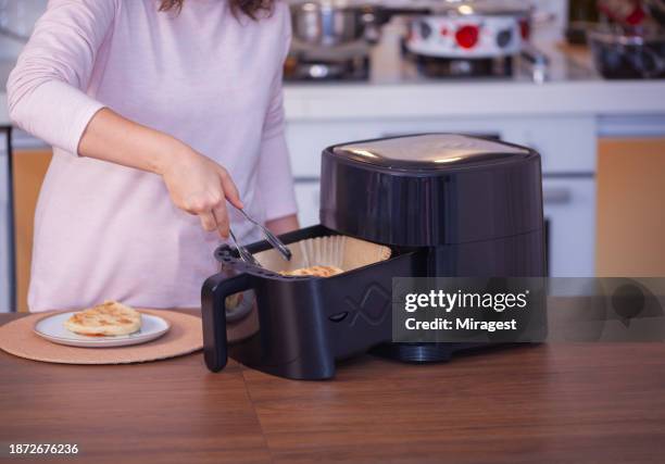 frau kocht essen mit heißluftfritteuse in der küche. - fritteuse stock-fotos und bilder