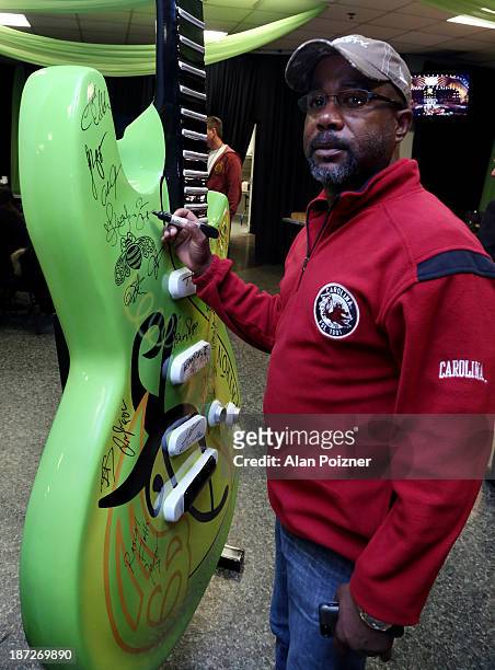 Darius Rucker signs a giant Patron tequila guitar backstage at the CMA Awards to benefit the "Keep the Music Playing" music education on November 3,...