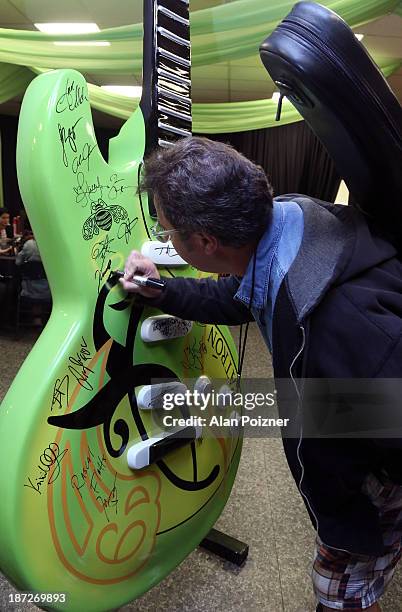 Vince Gill signs a giant Patron tequila guitar backstage at the CMA Awards to benefit the "Keep the Music Playing" music education on November 3,...