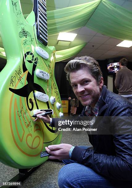 Joe Don Rooney of Rascal Flatts signs a giant Patron tequila guitar backstage at the CMA Awards to benefit the "Keep the Music Playing" music...