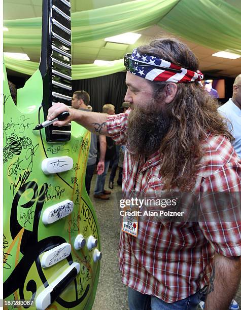 Willie Robertson of Duck Dynasty signs a giant Patron tequila guitar backstage at the CMA Awards to benefit the "Keep the Music Playing" music...