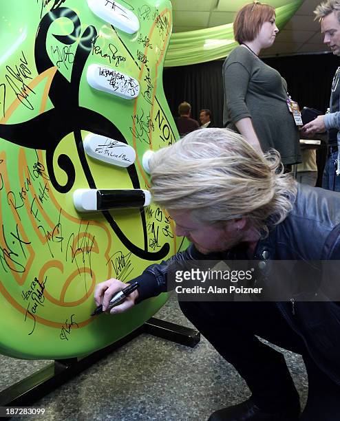 Phillip Sweet of Little Big Town signs a giant Patron tequila guitar backstage at the CMA Awards to benefit the "Keep the Music Playing" music...