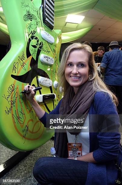 Korie Robertson of Duck Dynasty signs a giant Patron tequila guitar backstage at the CMA Awards to benefit the "Keep the Music Playing" music...