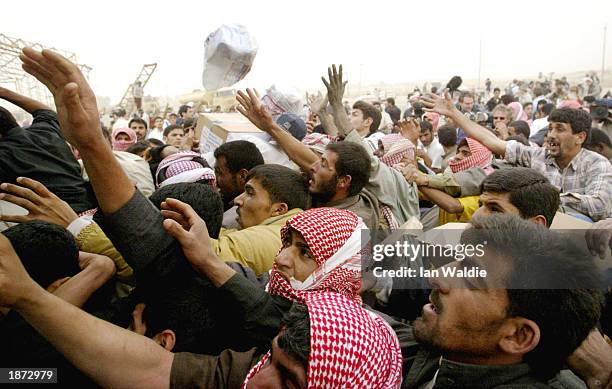 Hundreds of Iraqis gather at the back of a Red Crescent Society truck as humanitarian aid, in the form of food and water, is distributed March 26,...