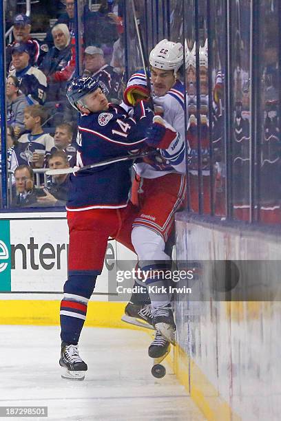 Blake Comeau of the Columbus Blue Jackets checks Brian Boyle of the New York Rangers into the boards while battling for control of the puck during...