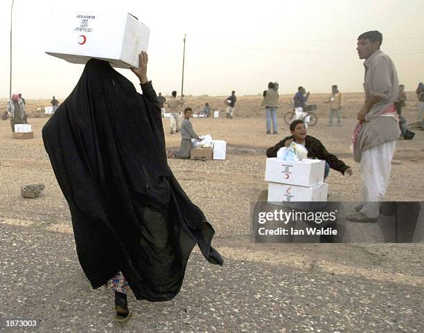 An Iraqi woman carries a humanitarian aid food package on her head as she walks away from a Red Crescent Society truck March 26, in Safwan, Iraq....
