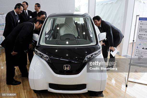 Attendees look at a Honda Motor Co. Micro Commuter prototype electric vehicle at an event at the company's Yorii plant in Yorii town, Saitama...