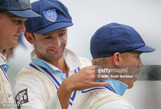 Nathan Lyon adjusts the collar of David Warners shirt as Doug Bollinger of the Blues looks on during day three of the Sheffield Shield match between...