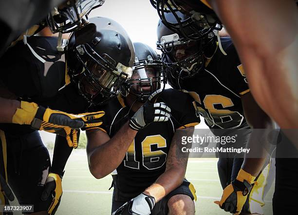 players gathered in a football huddle - quarterback stockfoto's en -beelden