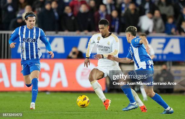 Jude Bellingham of Real Madrid runs with the ball whilst under pressure from Ianis Hagi and Antonio Blanco of Deportivo Alaves during the LaLiga EA...