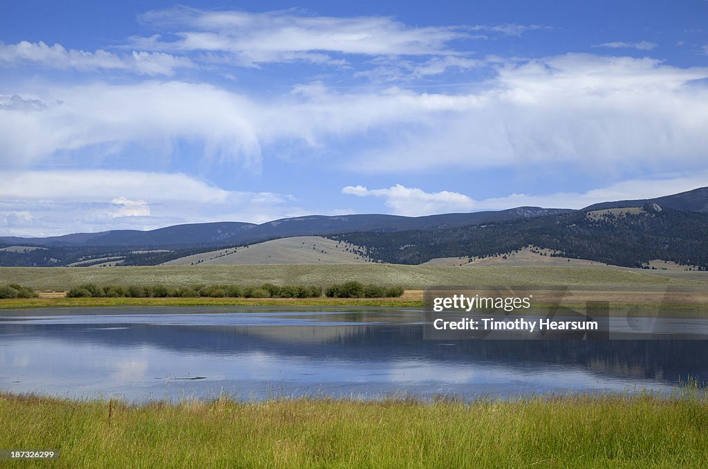 Lake surrounded by grasses, hills and sky beyond