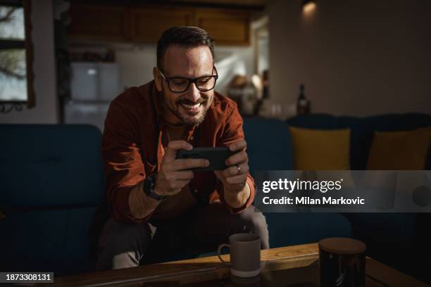 man playing video games on his smartphone - mobile game stock pictures, royalty-free photos & images