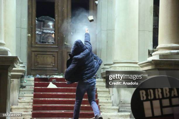 Protestors throw rocks staging a protest in front of Belgrade City Council building objecting to the result of general and local elections, in...
