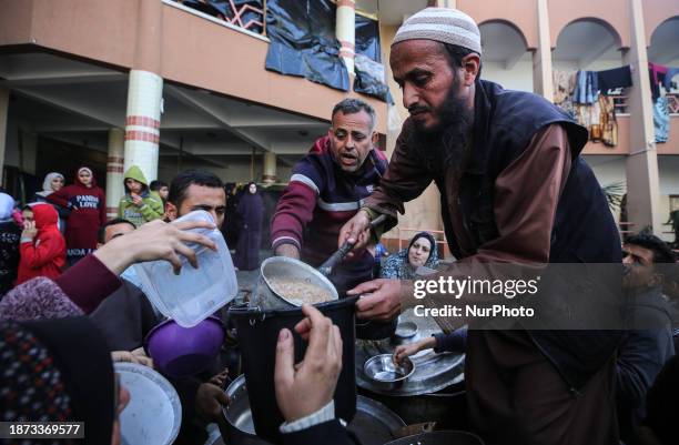 Palestinians are waiting to collect food at a donation point in a school that is sheltering Palestinians displaced by the conflict in Gaza between...