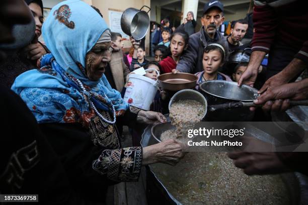 Palestinians are waiting to collect food at a donation point in a school that is sheltering Palestinians displaced by the conflict in Gaza between...