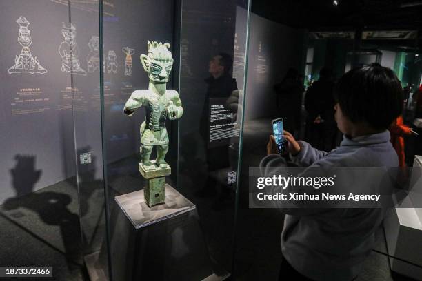 Visitor takes photos of a bronze relic from China's Sanxingdui Ruins during an exhibition titled "Glory of Bronze Civilization" in the Museum of...