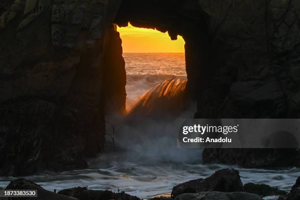 Sunray passes through Keyhole Arch during sunset at Pfeiffer Beach in Big Sur, California, United States on December 24, 2023.