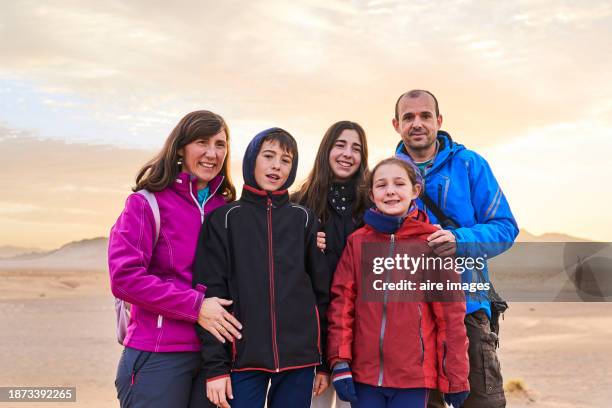 portrait of a family group standing embracing in the middle of the zagora desert smiling looking at the camera, front view - morocco stock pictures, royalty-free photos & images