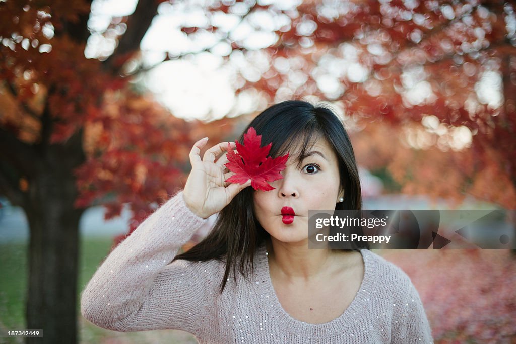 Woman holding red maple leaf