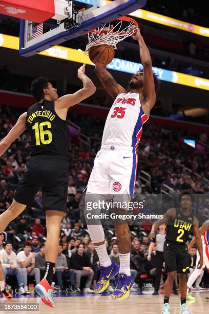 Marvin Bagley III of the Detroit Pistons dunks next to Simone Fontecchio of the Utah Jazz during the first half at Little Caesars Arena on December...