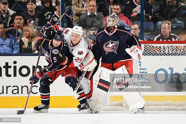 Fedor Tyutin of the Columbus Blue Jackets and Chris Neil of the Ottawa Senators battle for position in front of goaltender Curtis McElhinney of the...