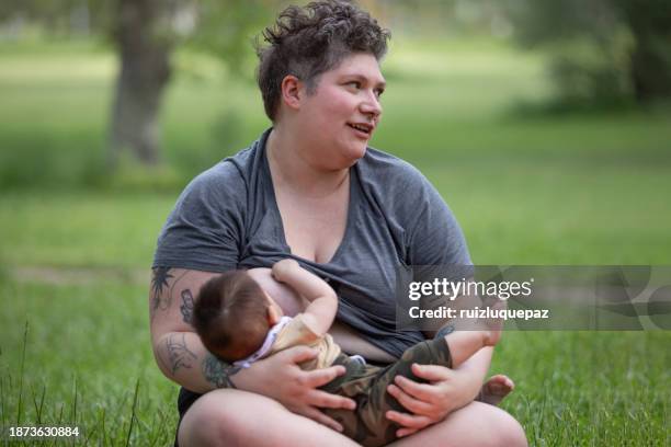 mother breastfeeding her baby in the park - animal teat stock pictures, royalty-free photos & images