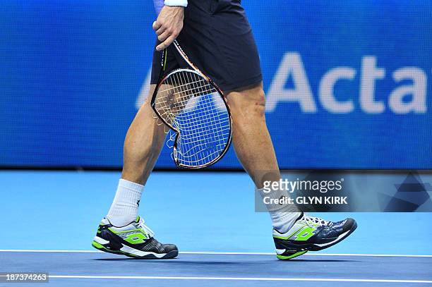 Spain's David Ferrer walks with his broken racquet after smashing it during his group A singles match against Switzerland's Stanislas Wawrinka in the...