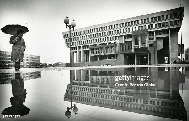 City Hall and a pedestrian were reflected in a puddle on City Hall Plaza.