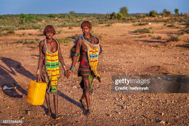 two african young women carrying water from the well, ethiopia, africa - omo valley stock pictures, royalty-free photos & images