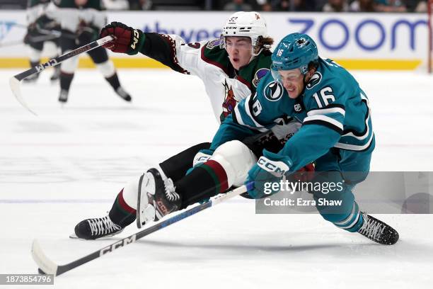 Logan Cooley of the Arizona Coyotes and Jack Studnicka of the San Jose Sharks go for the puck in the first period at SAP Center on December 21, 2023...