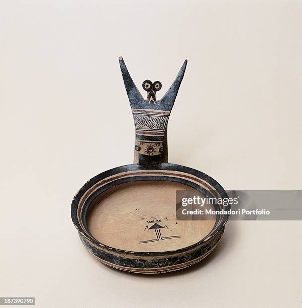 Italy, Puglia, Foggia, Museo Civico, Funerary simpulum, Small plate bearing a human figure with raised arms and wide open eyes on its side, It is...