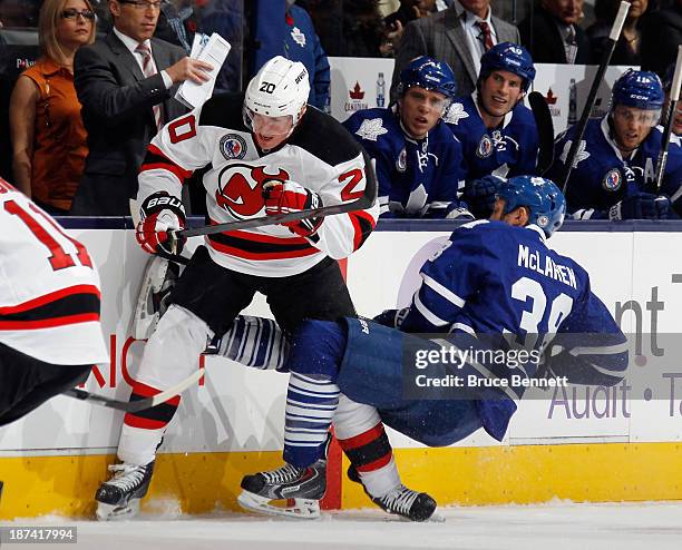 Ryan Carter of the New Jersey Devils checks Frazer McLaren of the Toronto Maple Leafs during the first period at the Air Canada Centre on November 8,...