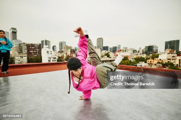 wide shot hip hop dancer balancing on hand while performing on rooftop - break dance city stock pictures, royalty-free photos & images