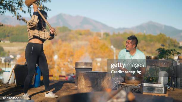 multiethnische touristin, die die japanische kultur erlebt und an einem mochitsuki-event in der natur teilnimmt - woman rural pounding stock-fotos und bilder