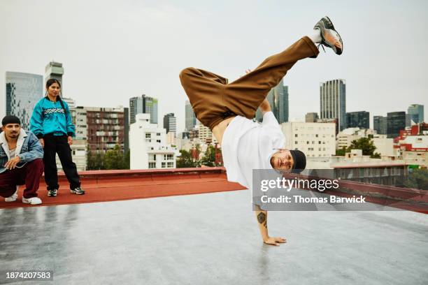 wide shot hip hop dancer balancing on one hand on city rooftop - breaking stock pictures, royalty-free photos & images