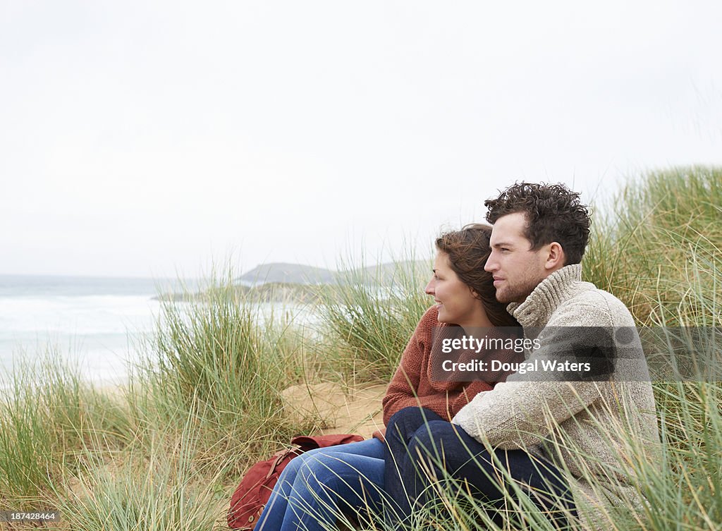 Couple sitting in dunes on Atlantic coastline.