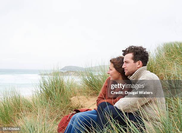 couple sitting in dunes on atlantic coastline. - couple dunes stock-fotos und bilder