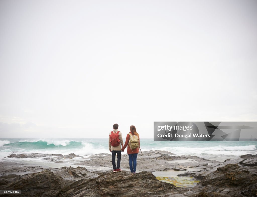 Couple holding hands and looking out to sea.